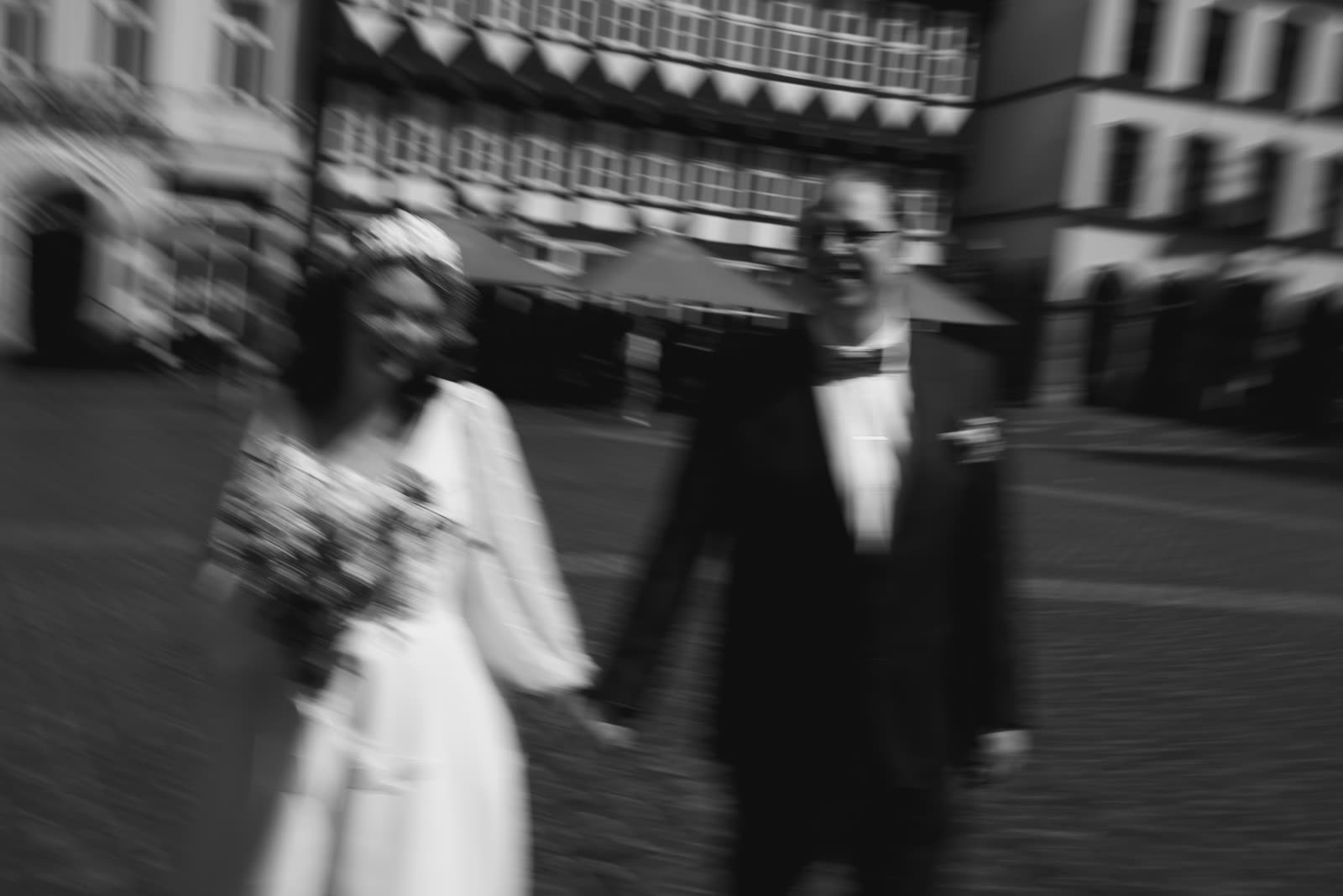 Brautpaar Hand in Hand vor historischer Kulisse – cinematische Schwarzweiß-Aufnahme